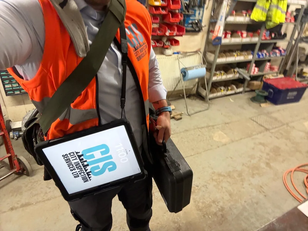 City Inspection Services engineer in branded hi-vis carrying a digital reporting tablet on site